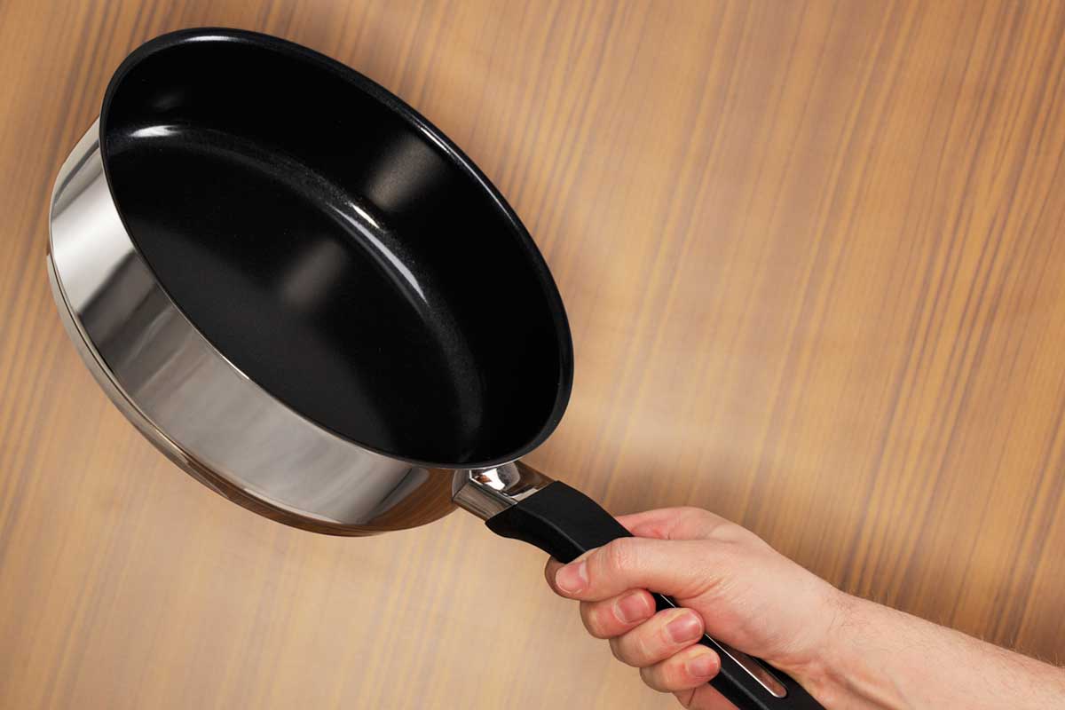 Man holding a nonstick saute pan with his right hand, Should A Saute Pan Be Nonstick?