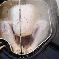 Sizzling turkey about to be cooked as it is lowered into a deep fryer, How Much Oil To Deep Fry A Turkey?