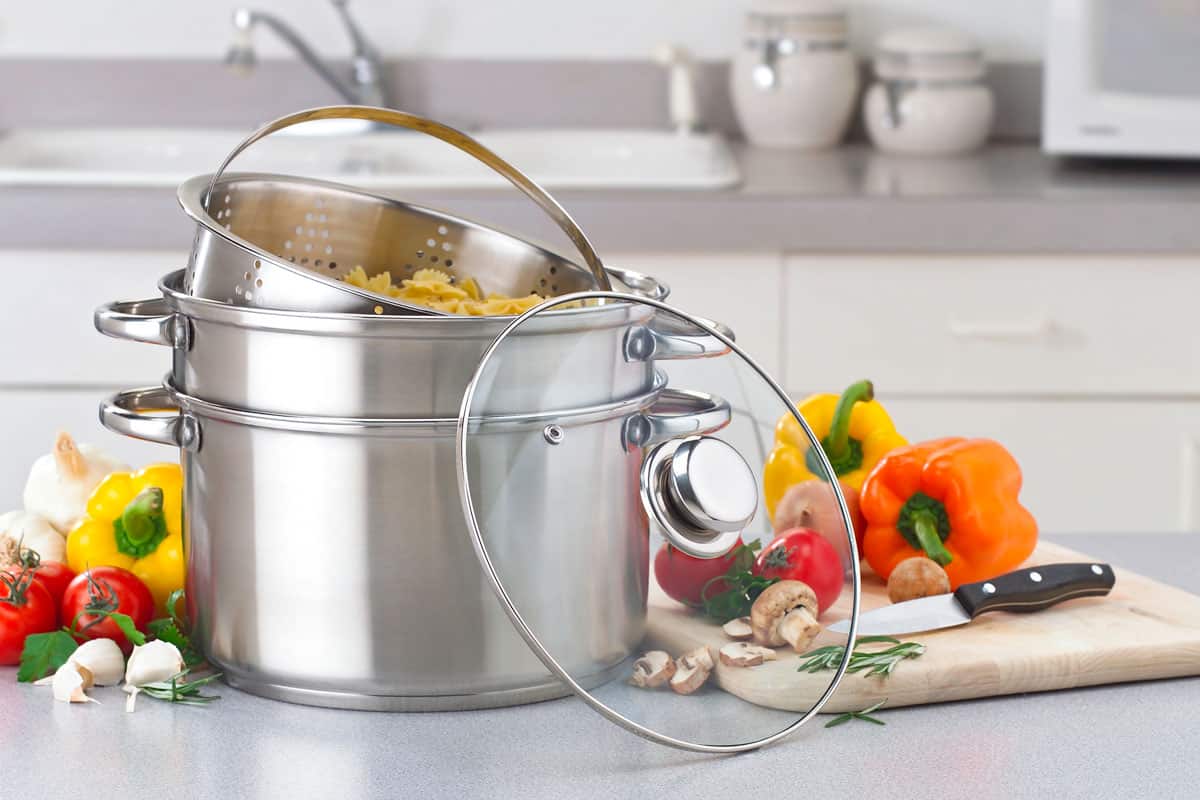 Double boiler with bell peppers at the side and chopping board with spices
