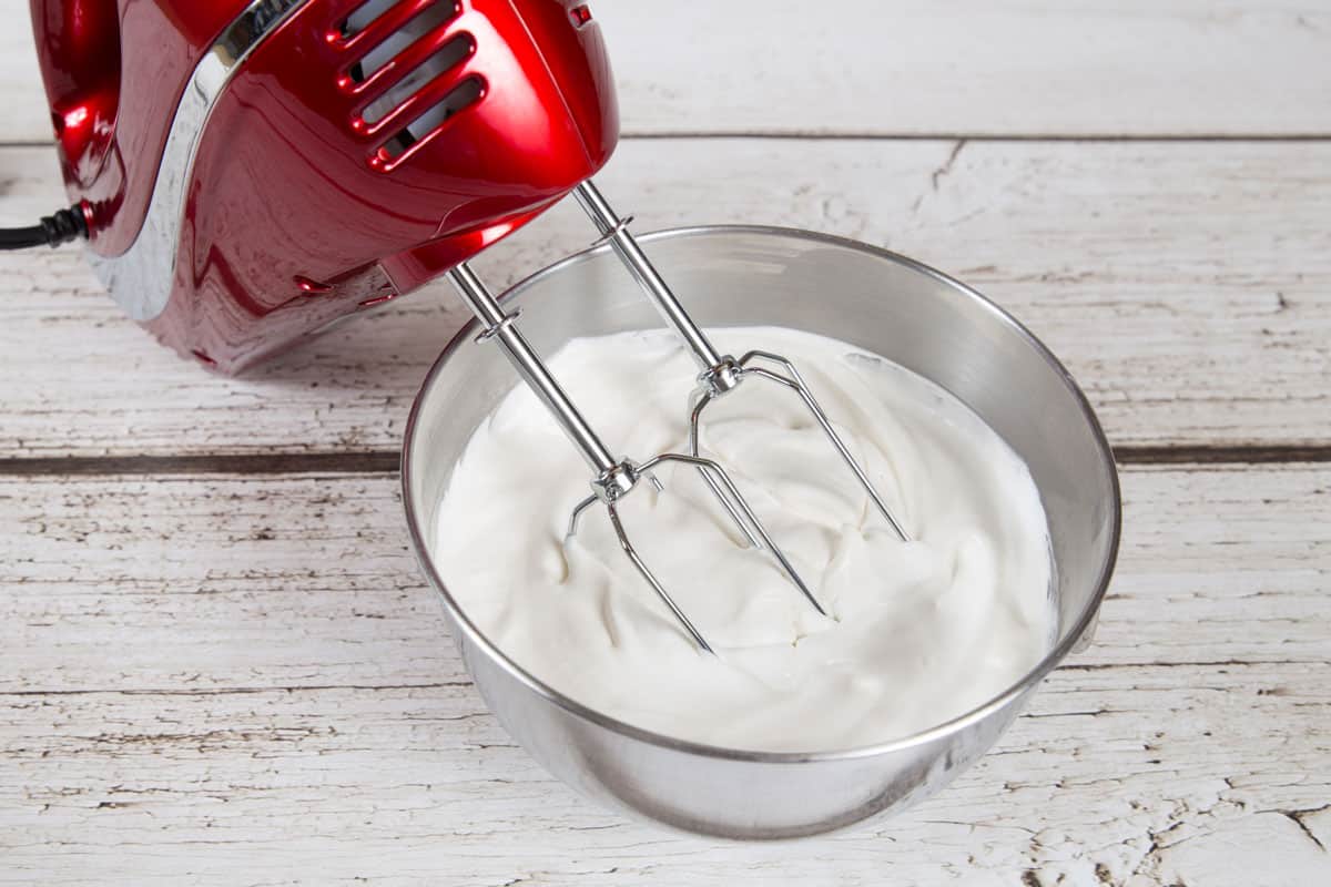 Red hand mixer mixing a mixture for cooking inside a metal bowl, Can I Use A Hand Mixer In A Metal Bowl?