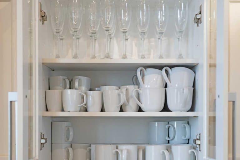 A shelf storage full of white mugs and champagne glasses, How to Store Glasses and Cups in The Kitchen