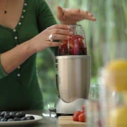 A young woman making a fruit smoothie drink using a nutibullet after loading it with fruit, My NutriBullet Stopped Working – What Could Be Wrong?