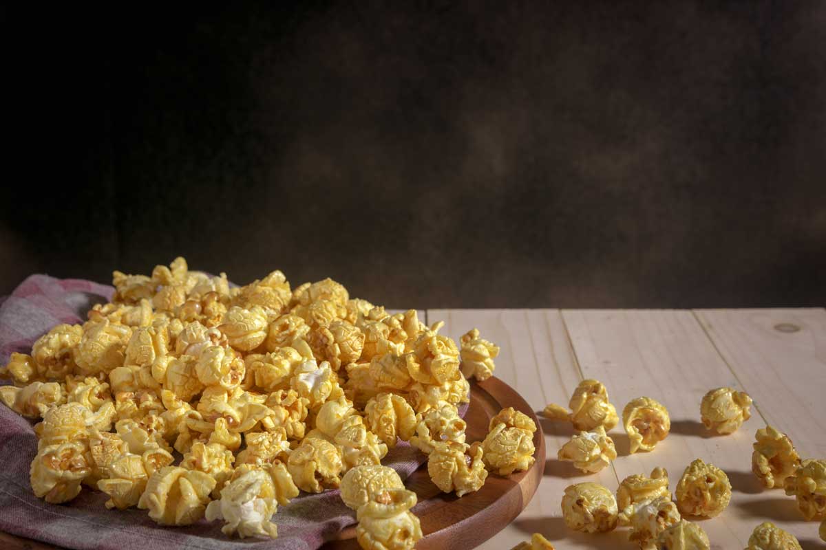 Caramel covered popcorn on wooden table,