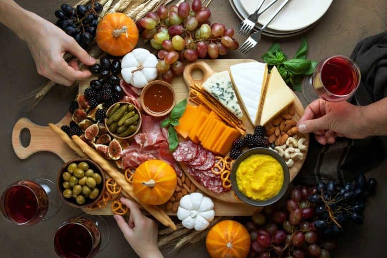Fantastic italian gifts presented at Fall holidays party table with friends hands picking some fingerfoods from charcuterie board, top down view, 15 Fantastico Italian Cooking Gifts