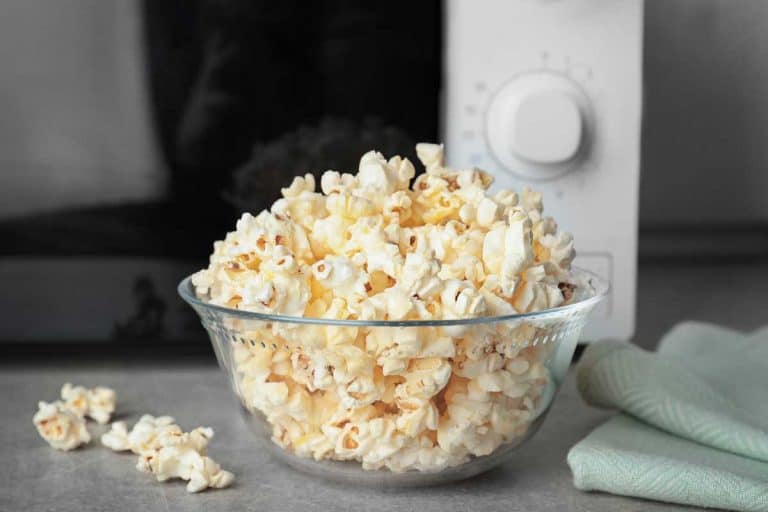 Glass bowl with tasty popcorn on table in kitchen and an oven toaster at the back, Can You Make Popcorn in a Toaster Oven? [Here’s How!]