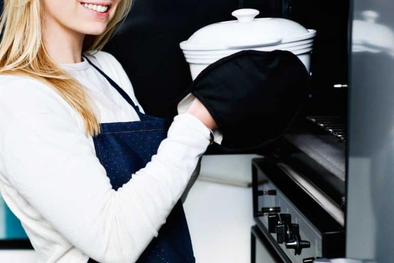 Lovely young blonde woman smiles as she takes a dutch oven from the oven, Can I Put A Dutch Oven In The Oven?
