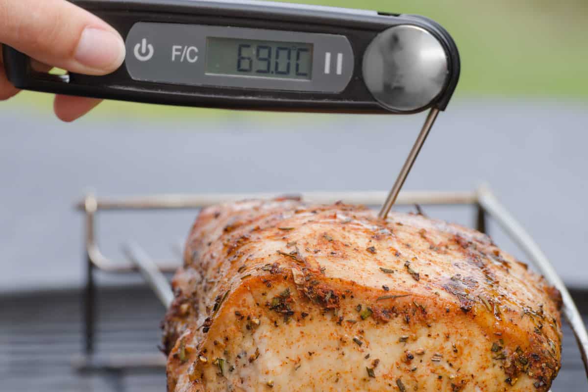 Man sticking meat thermometer on piece of beef
