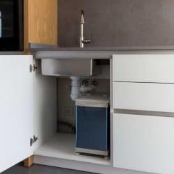 Opened kitchen cabinet with sink and installed garbage bin, 15 Awesome Under-Kitchen-Sink Storage Ideas