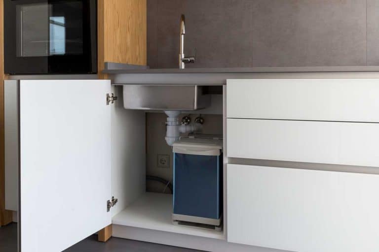 Opened kitchen cabinet with sink and installed garbage bin, 15 Awesome Under-Kitchen-Sink Storage Ideas