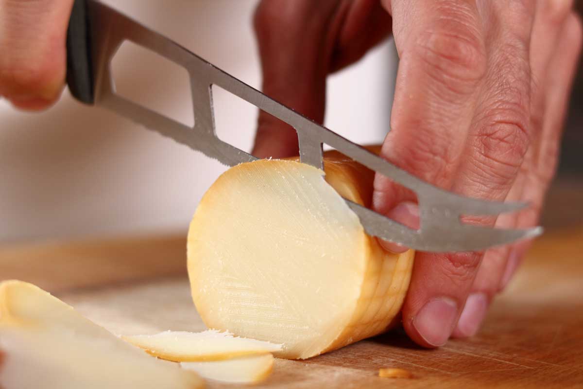 Slicing smoked cheese with cheese knife