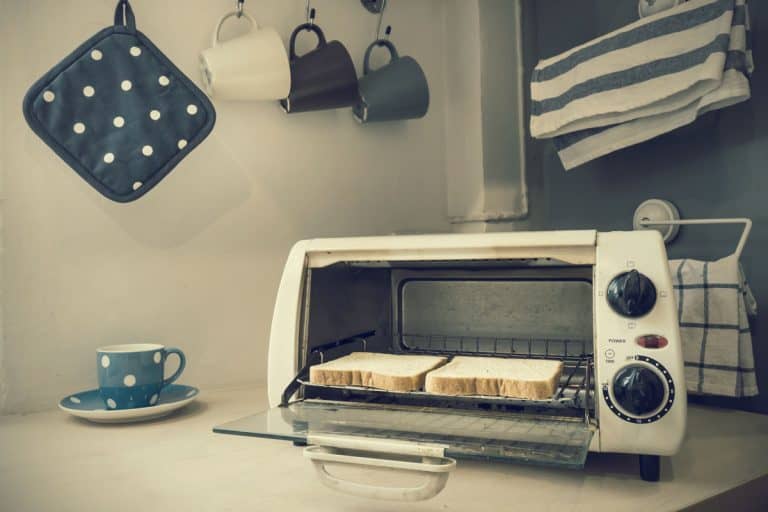 An old oven toaster with two loads of bread inside and hanging cups on the background, Where to Recycle A Toaster Oven?