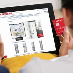 Woman shopping online with credit card buying refrigerator on tablet sitting on sofa at home, Where To Buy A Refrigerator? [Top 25 Online Stores]
