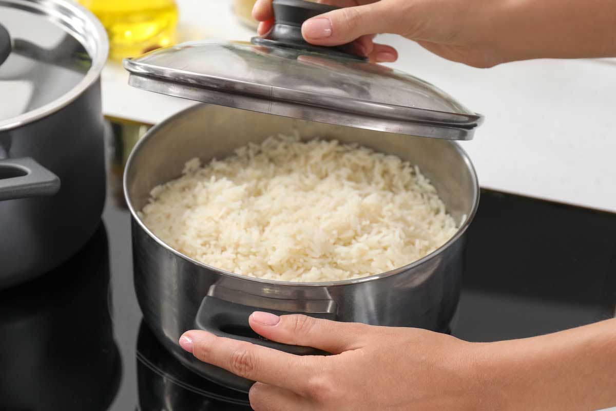Woman cooking rice on stove in kitchen, What’s the Best Pot for Cooking Rice? [Size and Type]