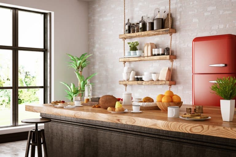 A modern kitchen with a butchers countertop and a hanging spice rack on the wall, How Much Do Butcher Block Countertops Cost? [By size, type, grain and brand]