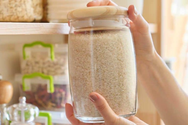 Woman taking a jar of rice in kitchen pantry, Does Rice Go Bad In The Pantry? [Inc. Tips for Keeping Rice Extra Fresh]