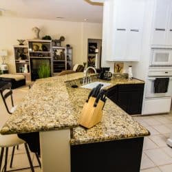 A classic style kitchen with a brown granite countertop and kitchen utensils placed on top, 14 Types of Kitchen Countertops (By Material)