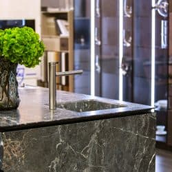 A luxurious modern kitchen with gray granite countertop with an indoor plant placed inside a jar, Are Granite Countertops Durable (And Easy To Maintain)?