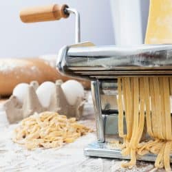 A pasta making machine making pasta with all the needed ingredients on the side, 5 Best Pasta Machine Brands You Should be Looking Into