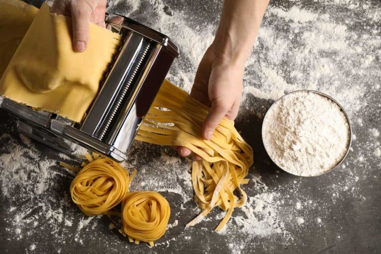 Woman preparing noodles with pasta maker machine at gray table, Dough Stuck In Pasta Machine - What To Do?