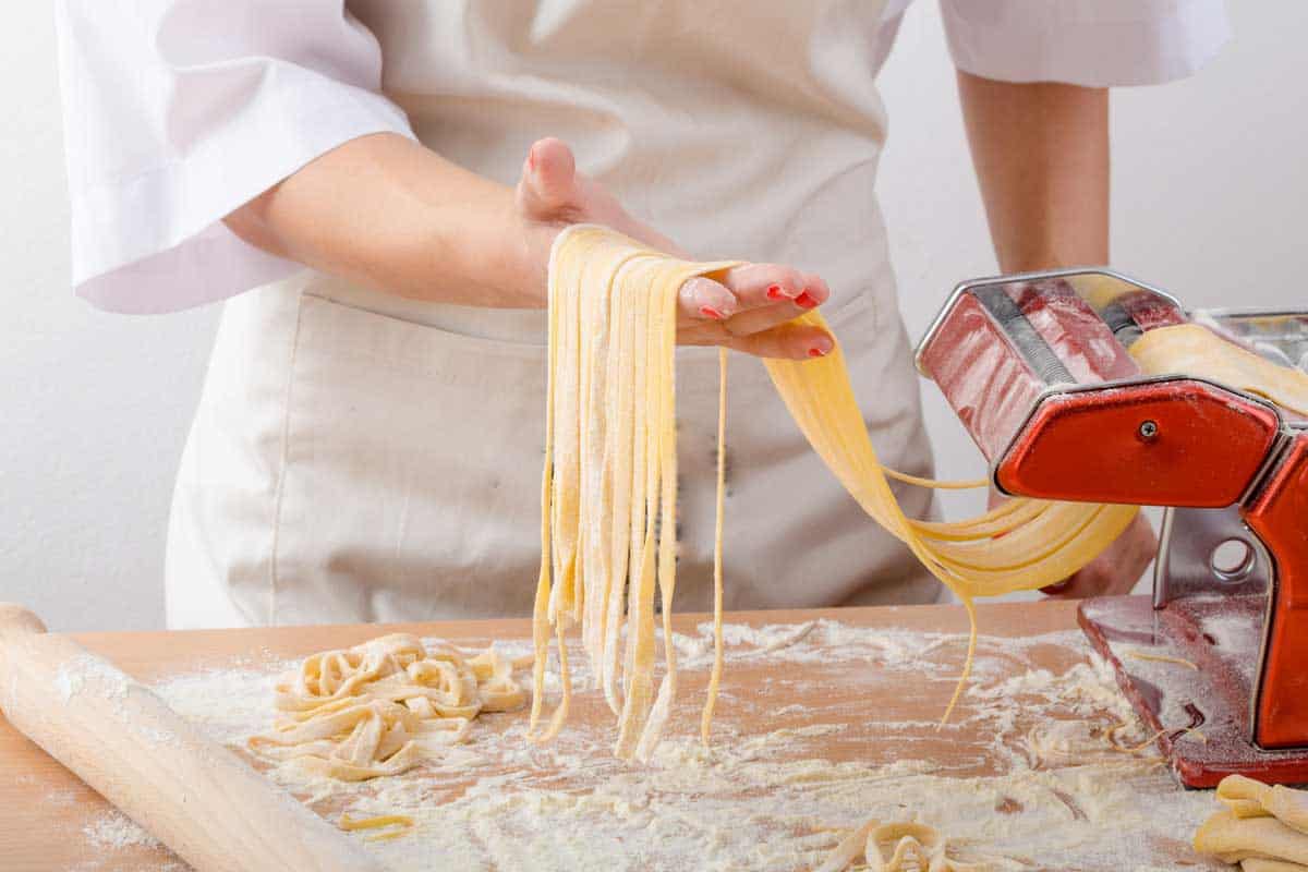 Young woman chef prepares homemade pasta from durum semolina flour