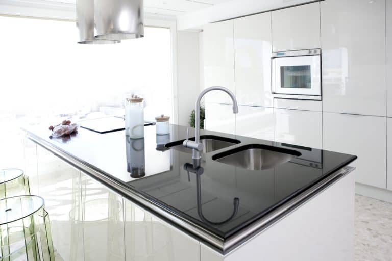 A dark granite colored countertop on a white themed kitchen, How Many Inches Can Granite Hang Without Support?