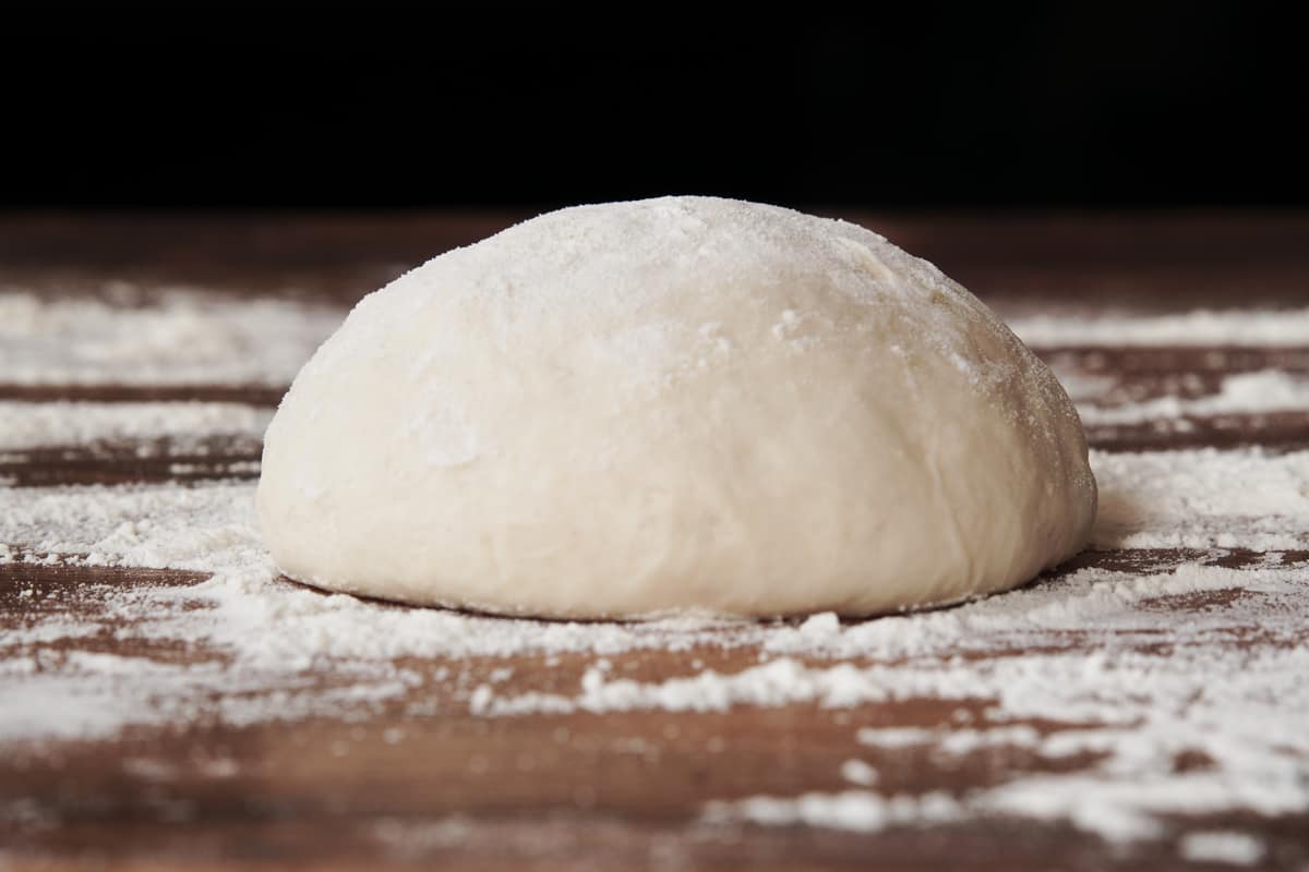A dough ball on a table with flour for a pizza dough