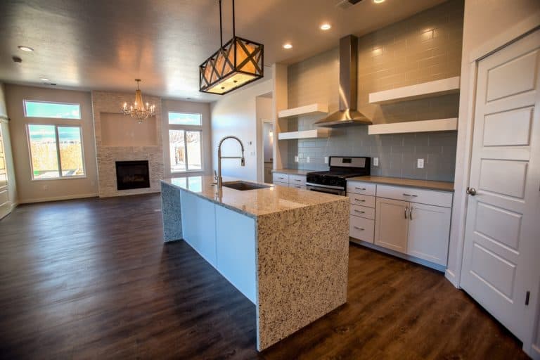 An empty kitchen with a granite island countertop with wooden flooring, How To Clean Granite Countertops? [3 Steps]