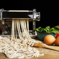 Pasta machine with noodles and ingredients on a wooden table, What Else Can You Use a Pasta Maker For? [9 Awesome Ideas!]