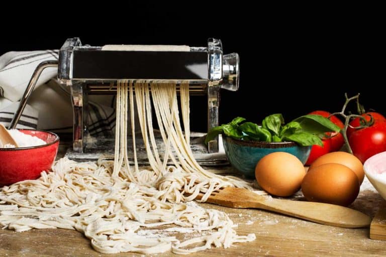 Pasta machine with noodles and ingredients on a wooden table, What Else Can You Use a Pasta Maker For? [9 Awesome Ideas!]