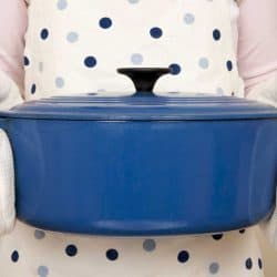 A woman wearing apron holding large blue casserole dish, Does A Casserole Dish Need A Lid? [Here's the Rule of Thumb]