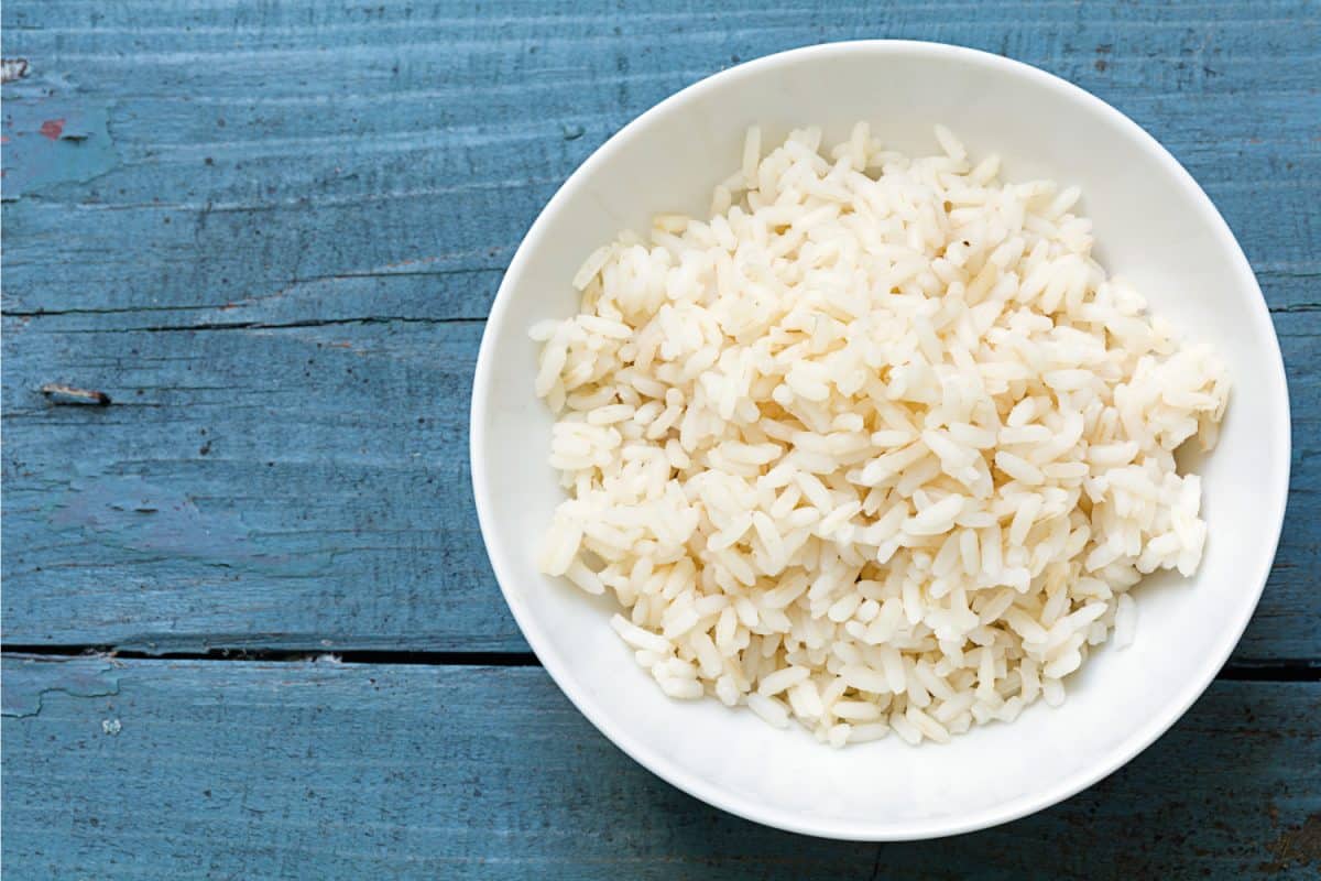 Boiled rice in a white china bowl on rustic blue wood