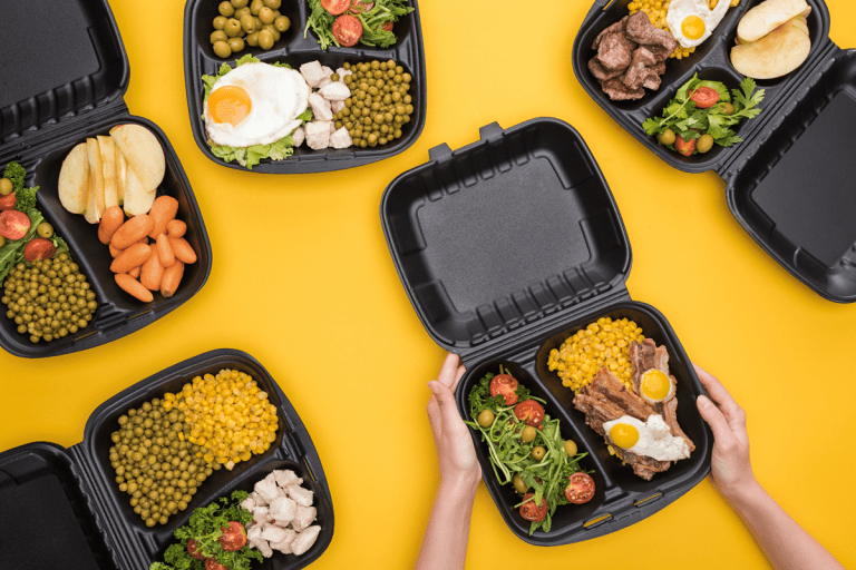 Cropped view of woman holding plastic food container with corn, meat, fried eggs and salad isolated on yellow stock, How to Remove Food Smells And Stains From Plastic Containers?