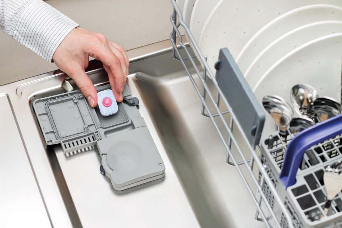 Man hand putting tablet in dishwasher detergent box