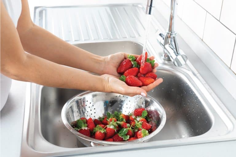 Woman is washing strawberry in the kitchen sink on a strainer, How To Strain Without A Strainer [8 ways]