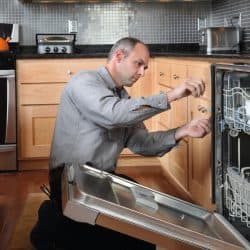 Worker repairing energy efficient dishwasher in contemporary kitchen, Whirlpool Dishwasher Not Spraying Water - What To Do?