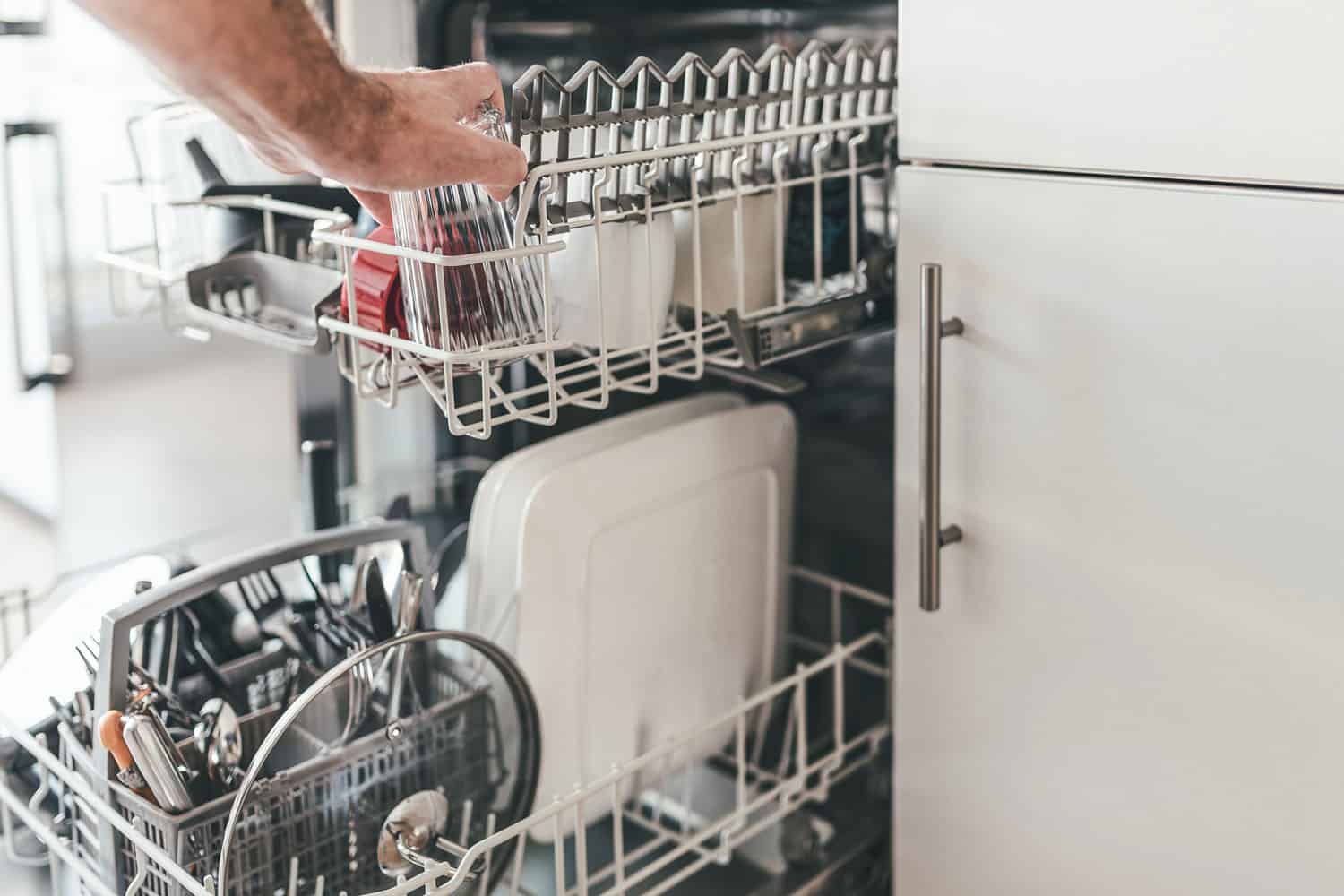 close-up of man loading or emptying dishwasher in kitchen, How To Winterize A Dishwasher?