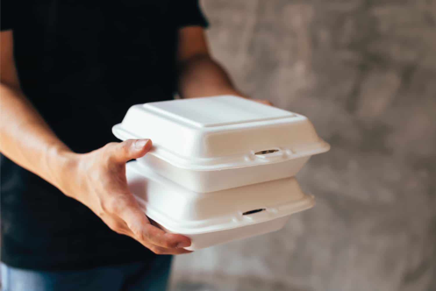 Delivery man handing a slack of foam lunch box