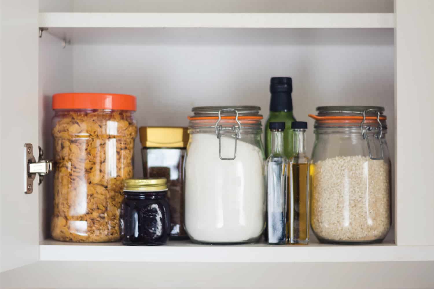 stocked kitchen pantry with food - glass jars and glass containers of cereals, jam, coffee, sugar, flour, oil, vinegar, rice