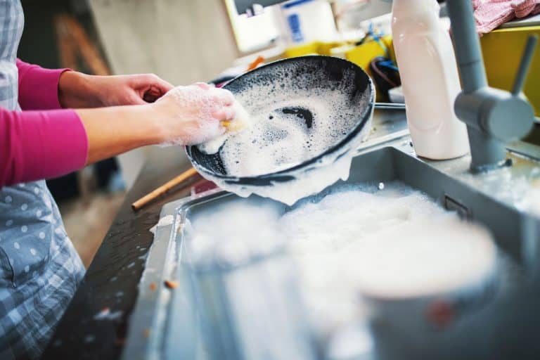 A woman washing a newly used frying pan, How Often Should You Wash A Frying Pan?