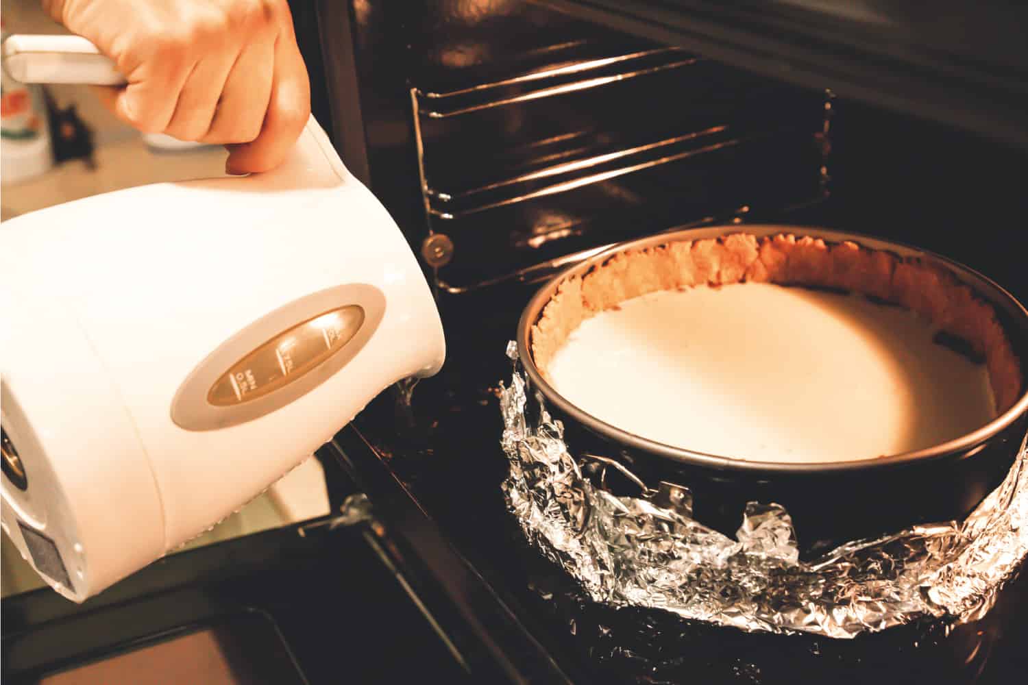 Cheesecake in the oven on a springform pan in foil