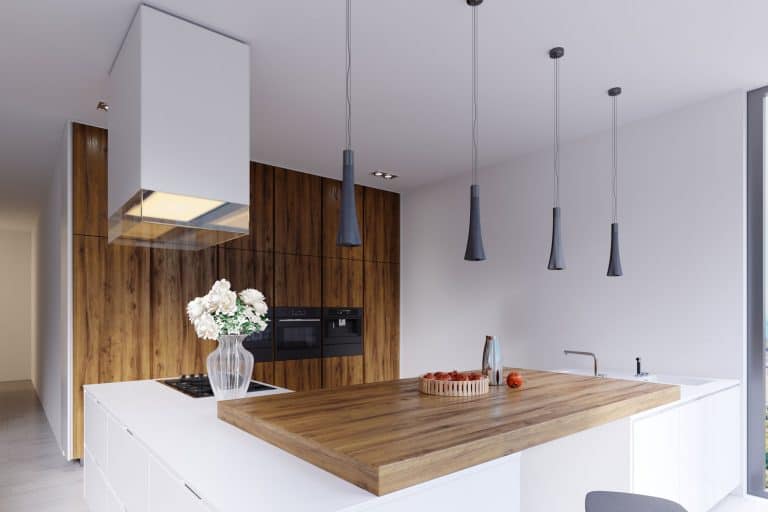Gorgeous minimalist themed with a wooden breakfast bar with dangling lamps, a freestanding kitchen range, and wooden paneled kitchen cabinets with an oven, Slide In Vs Freestanding Range - Which Should You Choose?