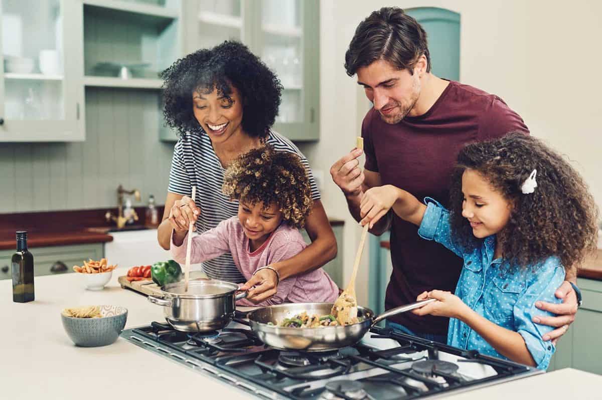 Shot of a family of four cooking together in their kitchen at home