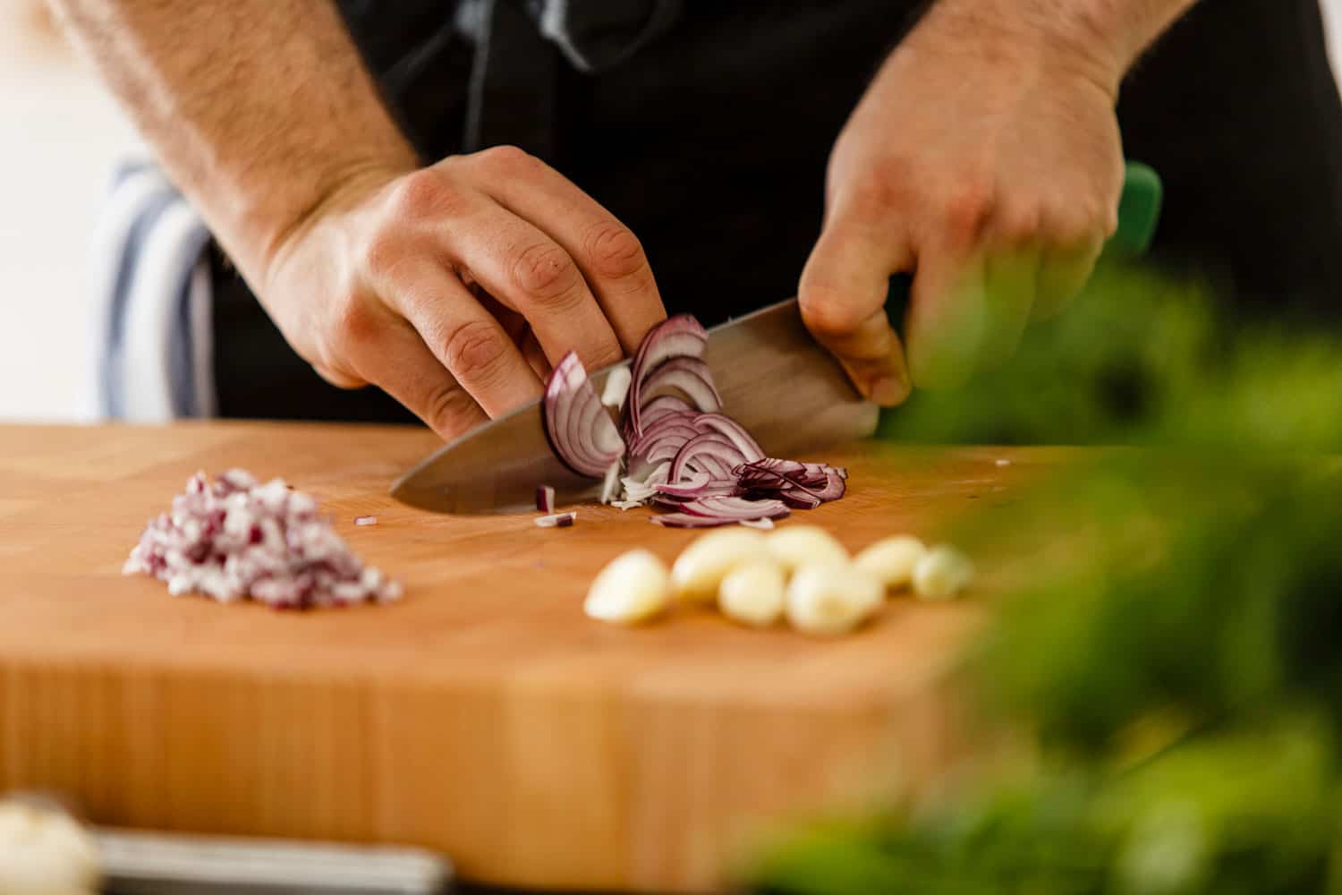 Chef slicing red onion on cutting board, close-up