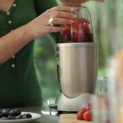 Woman making a fruit smoothie drink using a high speed blender after loading it with fruit, Can You Put Ice In A Nutribullet?