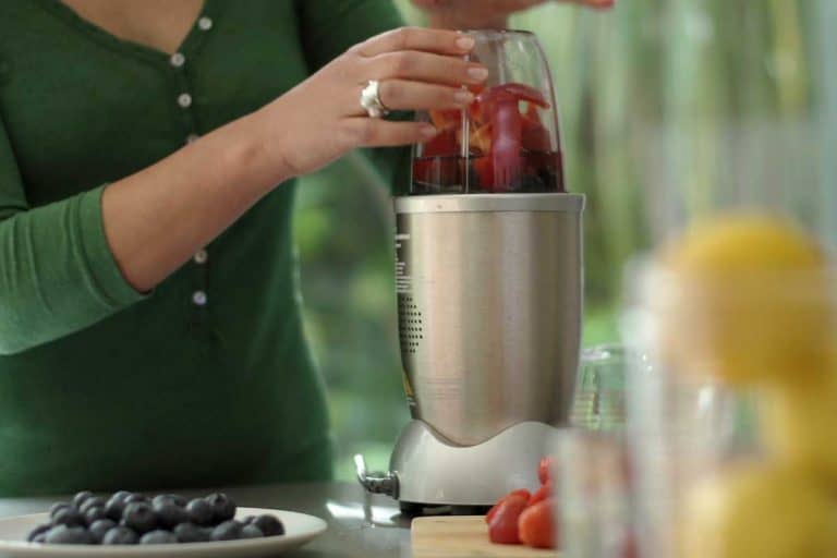 Woman making a fruit smoothie drink using a high speed blender after loading it with fruit, Can You Put Ice In A Nutribullet?