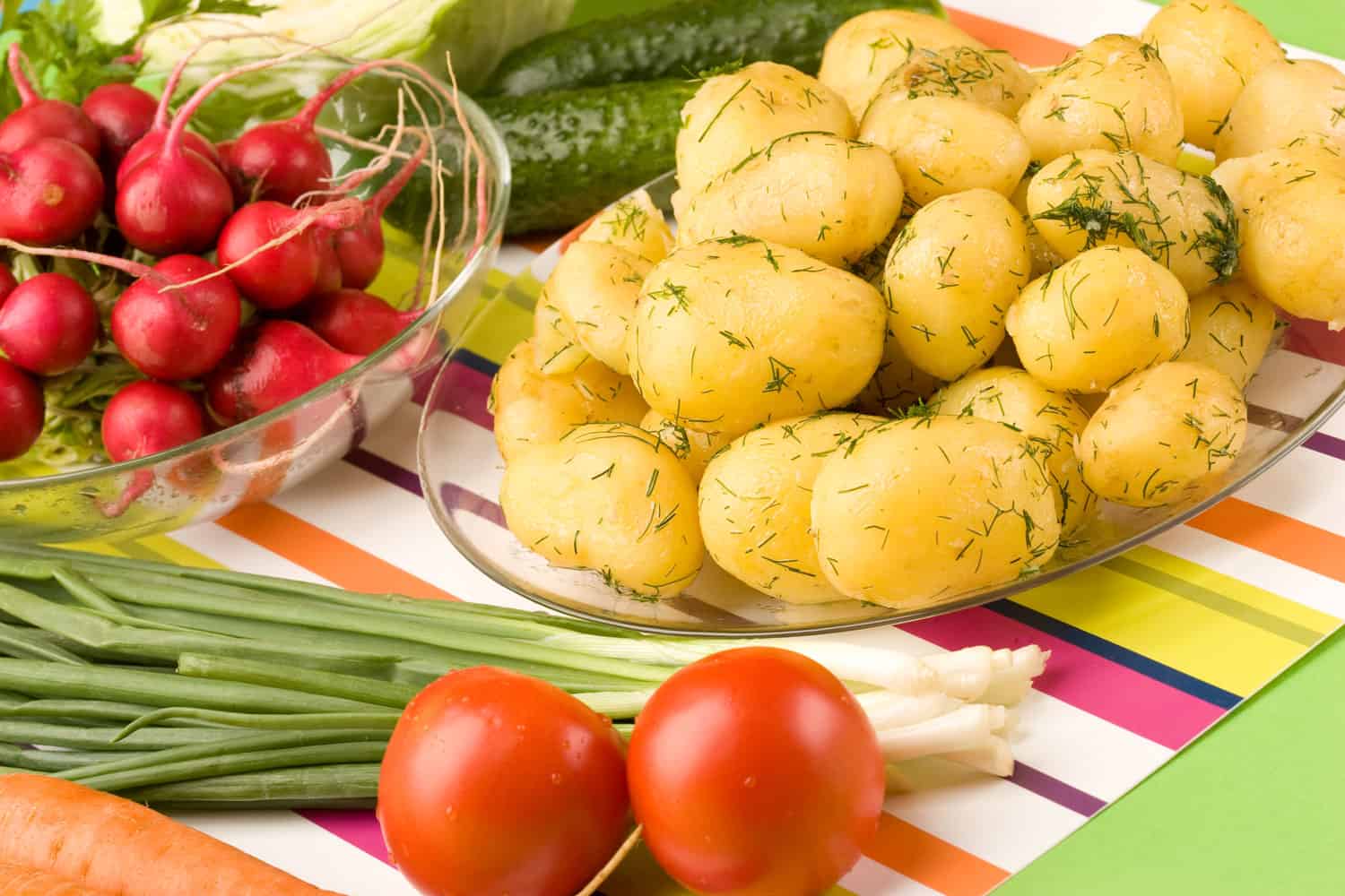 Peeled and boiled potatoes sprinkled with dill on a glass platter