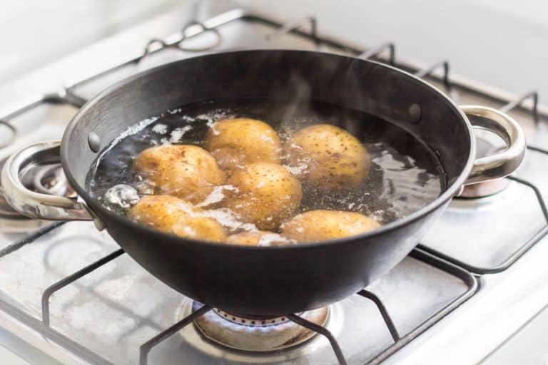 Potatoes placed inside a sauce pan under boiling water, Should You Peel And Cut Potatoes Before Or After Boiling?