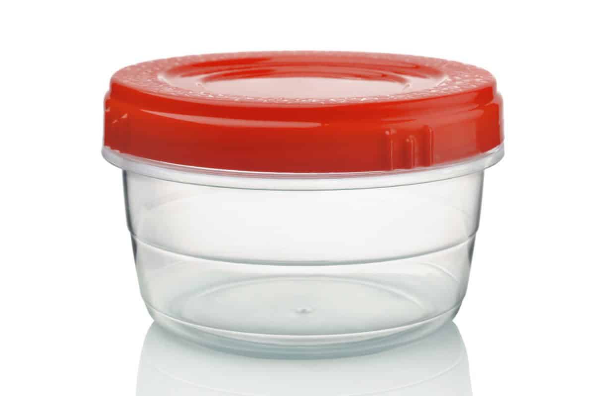 A plastic tupperware with a red lid on a white background