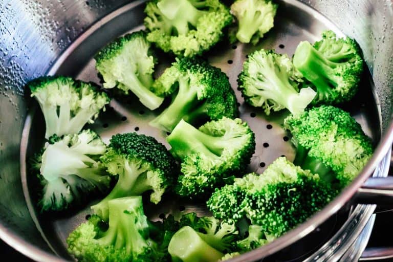Broccoli florets being cooked in a steamer, How To Steam Broccoli [With Or Without A Colander]