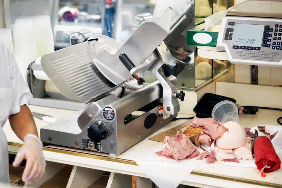 Butcher store counter with cold cuts next to a meat slicer, Can You Slice Meat In A Food Processor?